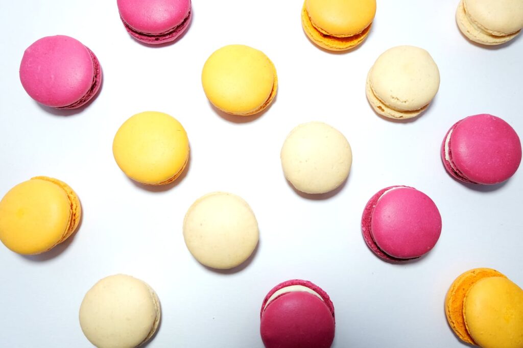 Brightly colored macarons arranged in a flatlay on a white background, perfect for dessert-themed imagery.